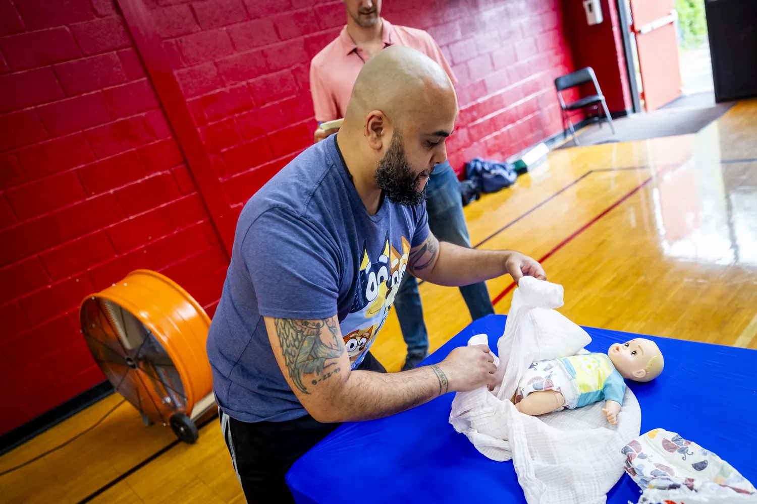 A dad changing a practice doll's diaper on a table